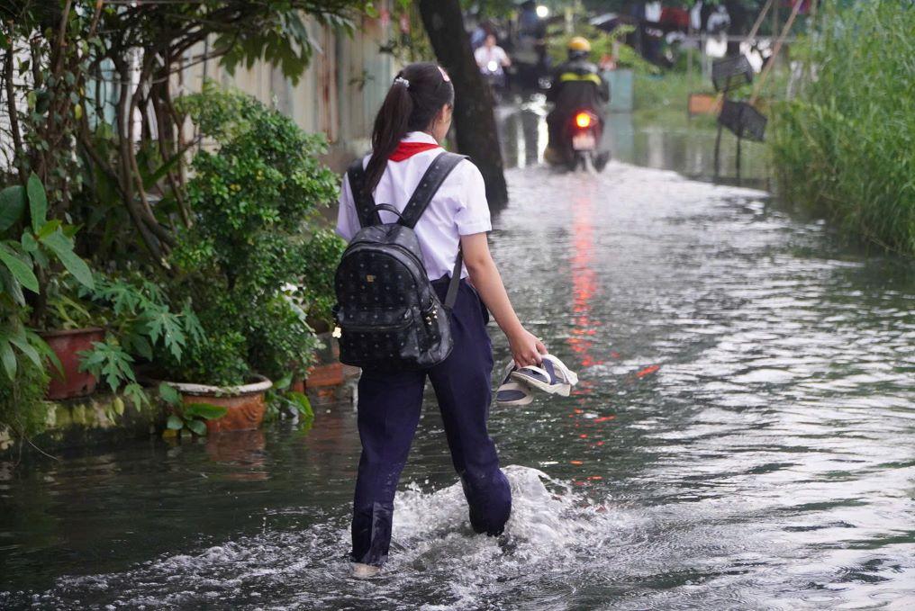 Học sinh TP.HCM lội qua tuyến đường ngập nước trong đợt triều cường.