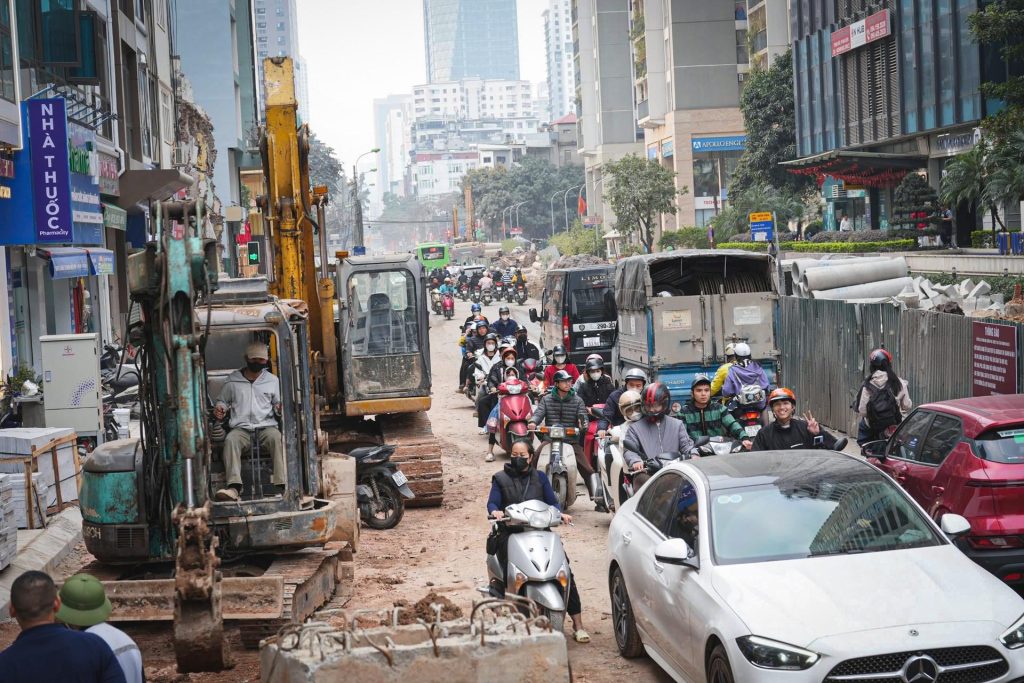 Xe máy và ô tô di chuyển qua tuyến đường Nguyễn Tuân, Hà Nội đang thi công nhiều bụi.