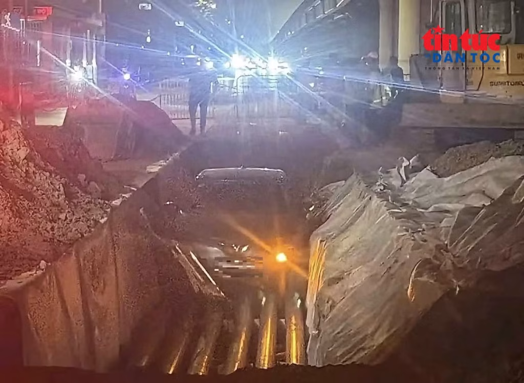 Lực lượng chức năng sử dụng xe cẩu đưa ô tô mắc kẹt ra khỏi hào cáp điện trên đường Phạm Hùng.