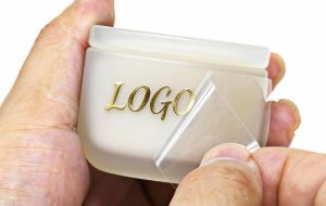 Tem UV DTF tạo hiệu ứng logo nổi bóng trên chai lọ mỹ phẩm.