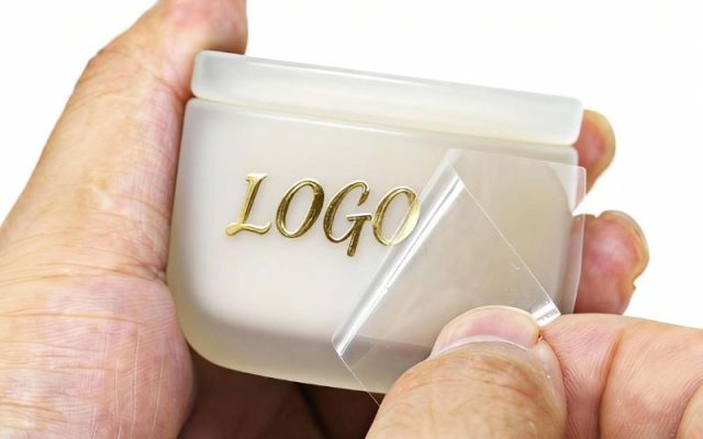 Tem UV DTF tạo hiệu ứng logo nổi bóng trên chai lọ mỹ phẩm.